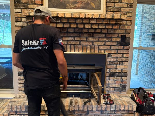 Fireplace company cleaning a fireplace on a brick wall in Grand Prairie, Texas.