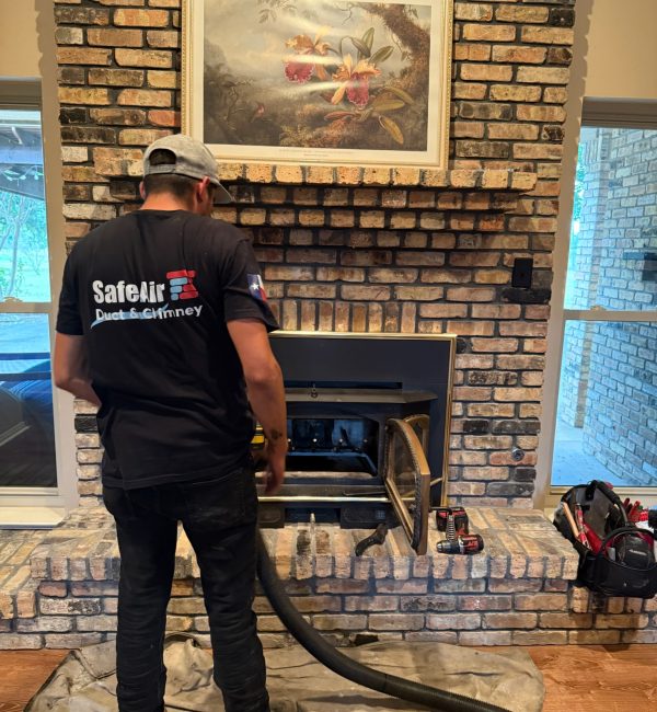 Fireplace company cleaning a fireplace on a brick wall in Grand Prairie, Texas.