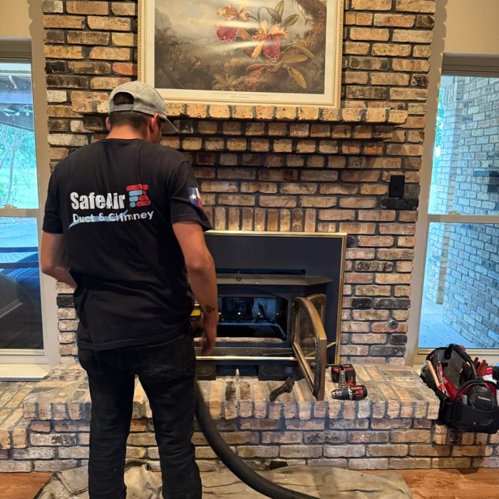 Fireplace company cleaning a fireplace on a brick wall in Grand Prairie, Texas.