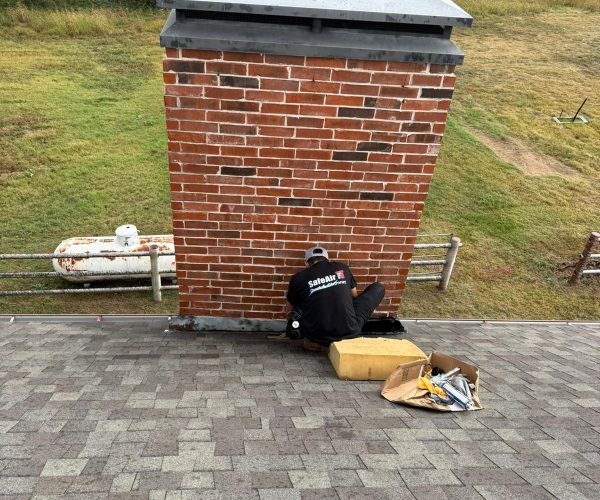 Red brick chimney undergoing flashing repair by a chimney company in Dallas, Texas.